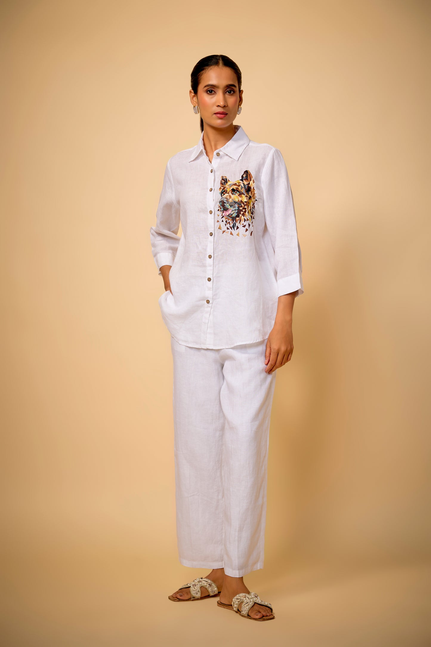 Woman wearing a white outfit with a patterned shirt against a beige background