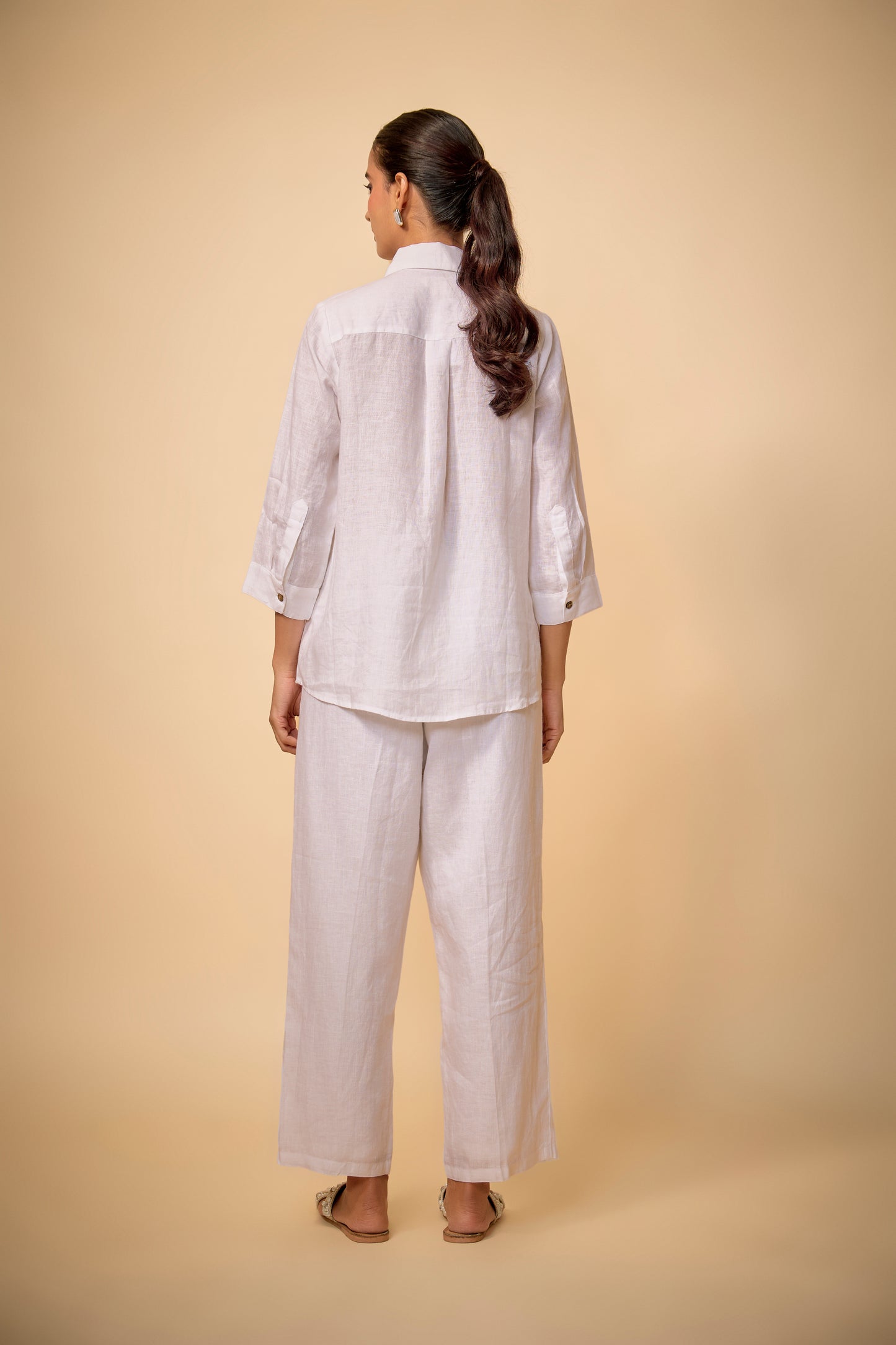 Woman wearing a light-colored outfit against a beige background